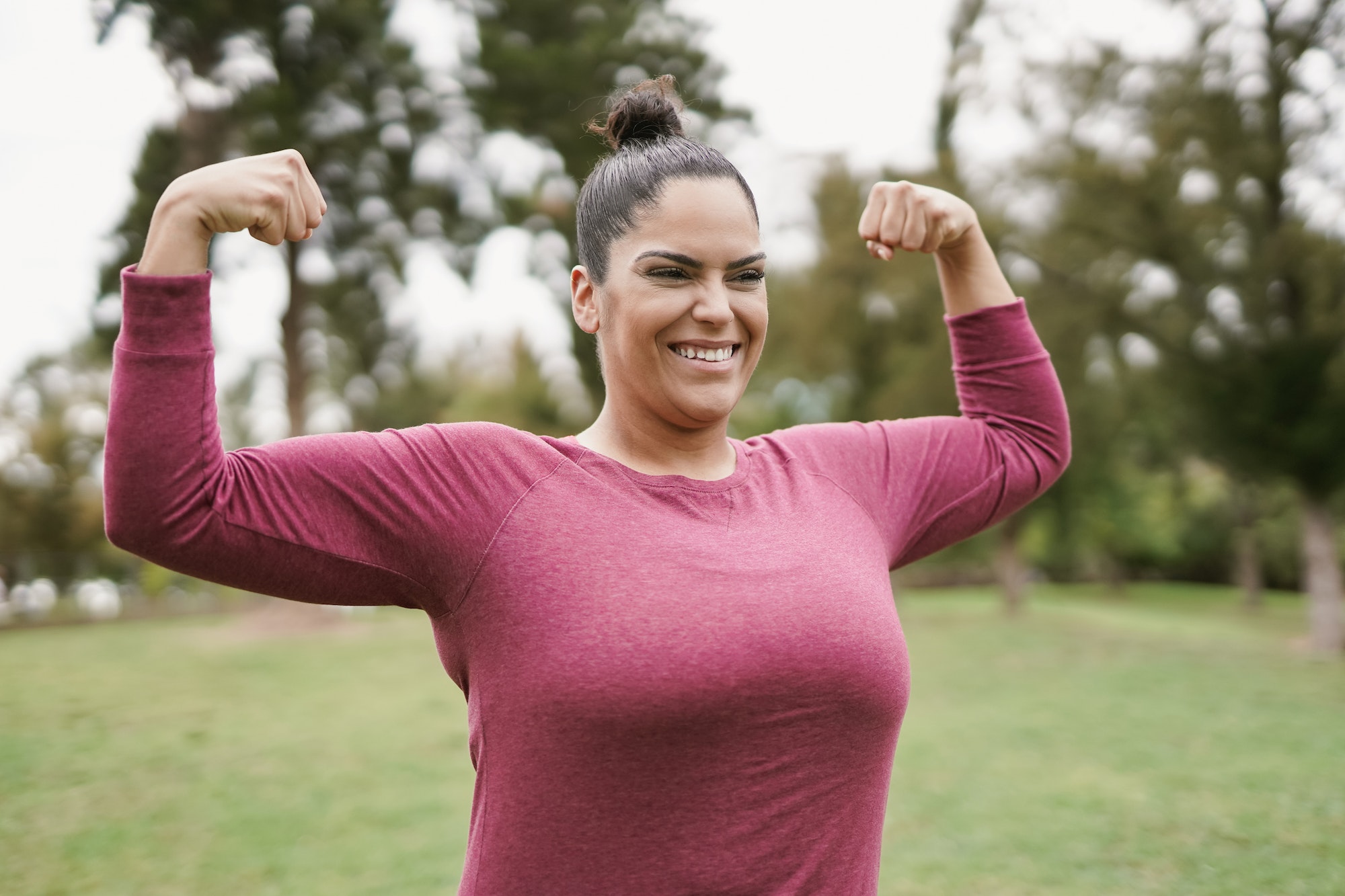 Curvy woman posing in front of camera showing muscle biceps